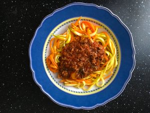 Ein Teller Zucchini-Karotten-Julienne mit Bolognese-Sauce.